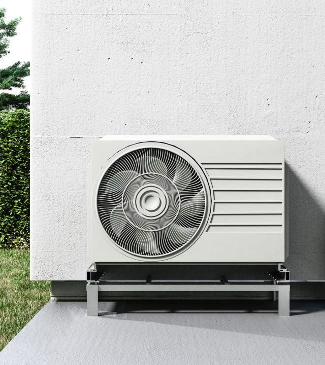 Sistema de aerotermia instalado en el exterior de una vivienda, con unidad exterior y conexiones hacia el interior para calefacción y agua caliente.